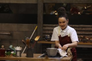 a female chef picking up a pot over a stove top on Next Level Chef