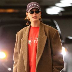 Hailey Bieber wears Shop Form black zip up sweatshirt with fold over black pants and black adidas samba sneakers.