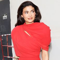 Kylie Jenner wears a red dress and looks away from the camera