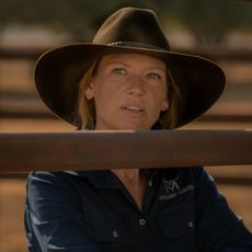 Anna Torv as Emily Lawson, standing behind a wooden fence, in 'Territory.'