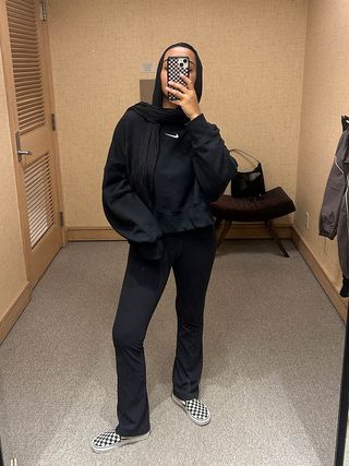 Yusra wears black leggings with vans sneakers, and a black nike sweatshirt.