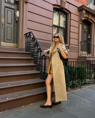 Eliza Huber wearing a gold Khaite minidress with a long Aligne trench coat.