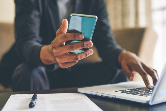 Man looking at phone working on lap top