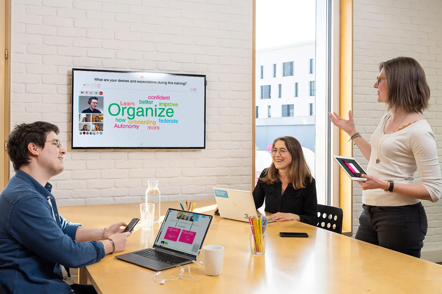 A training group interacting on a big screen with a word cloud, on site and remotely