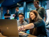 Seamless employees working together around a laptop.