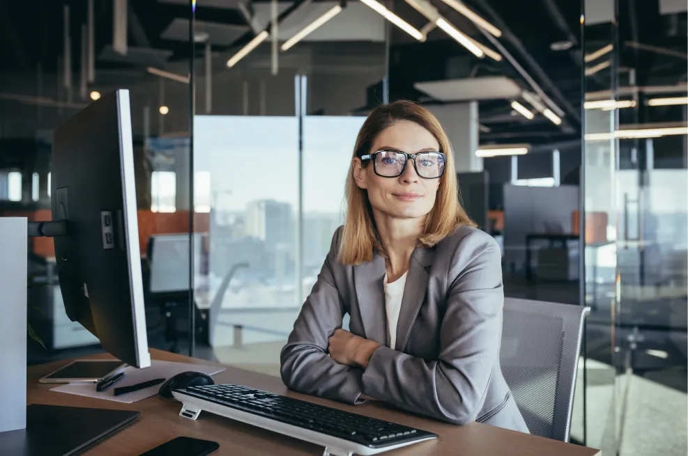 A woman sitting at a desk with a computer and keyboard.