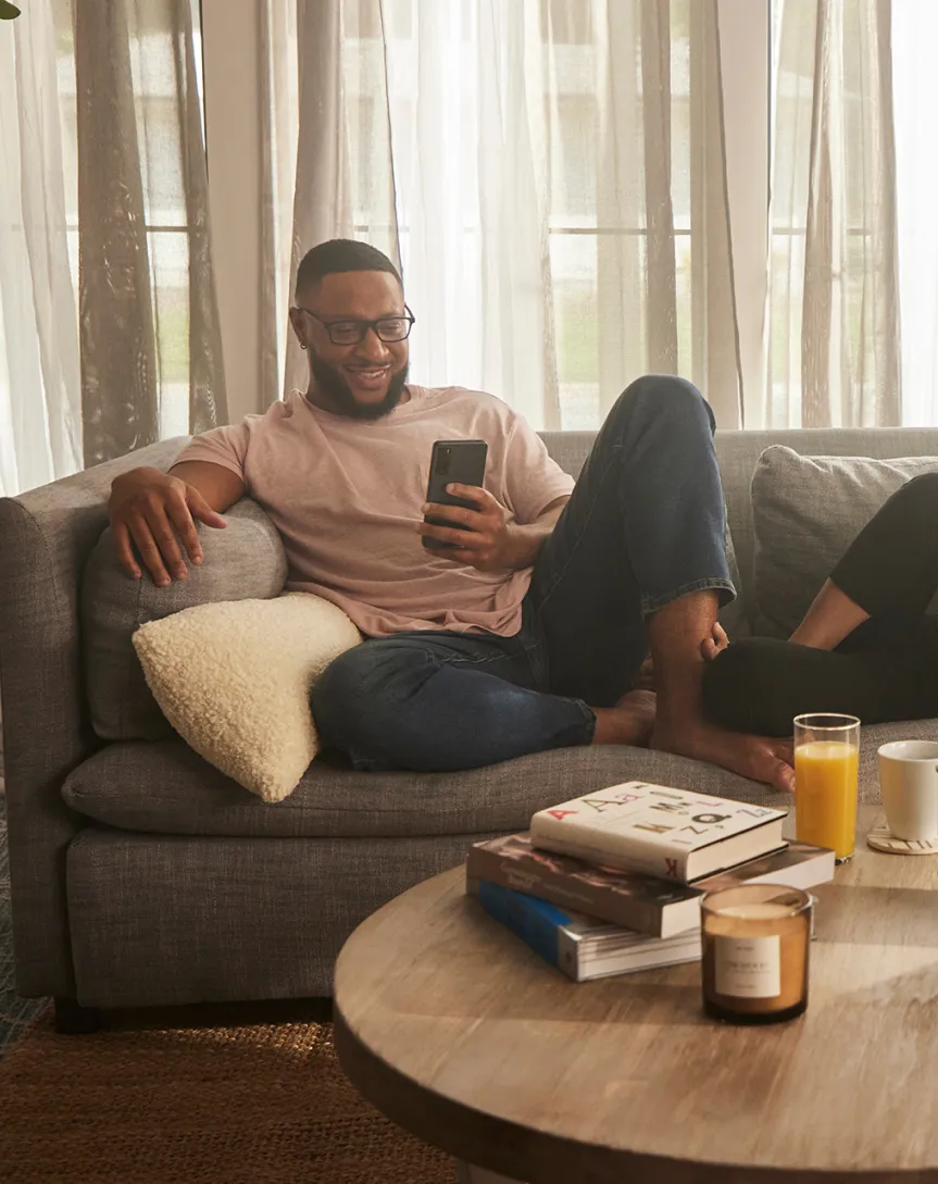 A man sitting on a couch and looking at his phone.