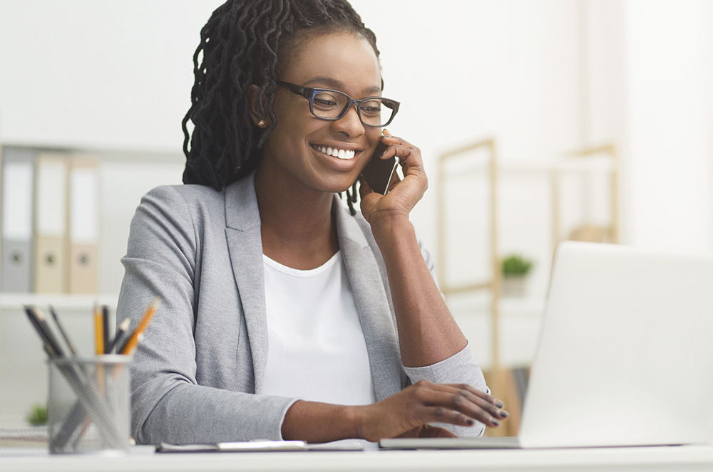 woman talking on phone while working on laptop