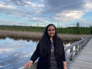 Sana Maqsood standing outdoors on a wooden bridge