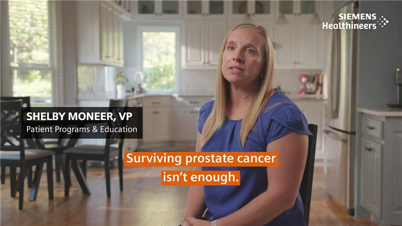 Woman in a blue shirt sitting in a chair with kitchen in the background. Overlay text says "Shelby Moneer, VP Patient Progress & Education."