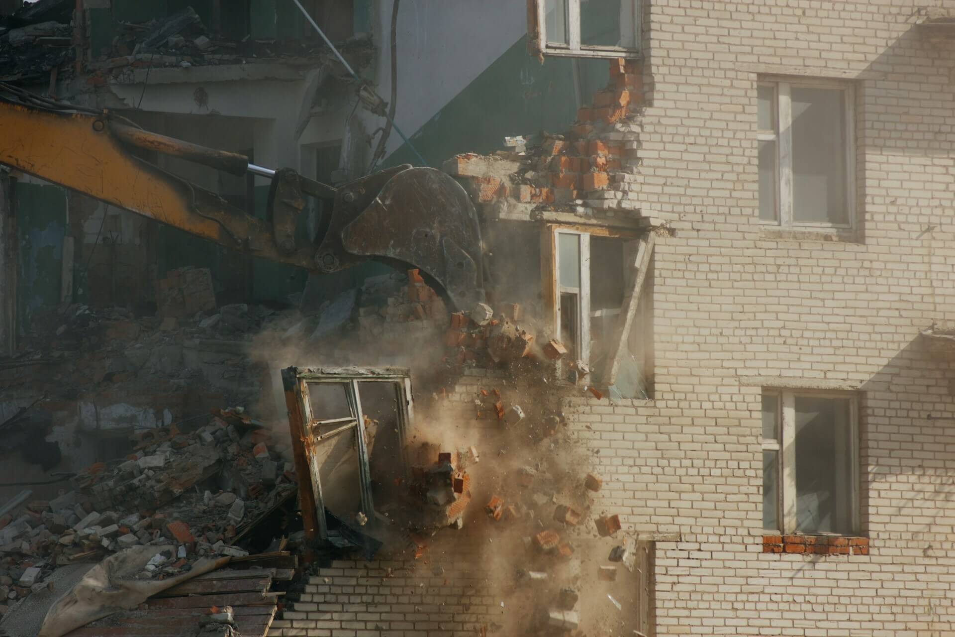 Abriss einer bereits eingerissenen Haus-Wand durch Baggerschaufel