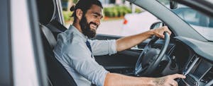 Young man in car adjusting radio