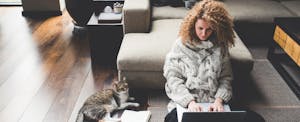 Woman sitting on the floor in her living room, working on her laptop