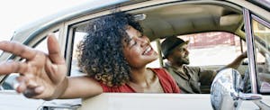 Two people enjoying an afternoon ride in a classic car