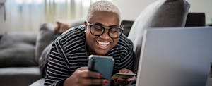 Young person smiling as they look at their Wells Fargo credit card and consider a credit limit increase