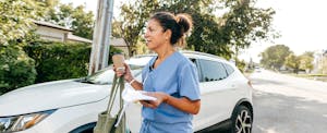 Nurse walking by her white car on the way to work.