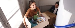 Young couple moving in to their new home and carrying boxes upstairs.