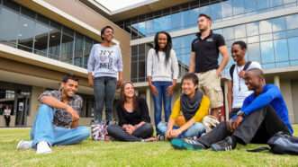 A diverse group of college students sits together outdoors. | Michael Turner | Dreamstime.com