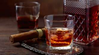 Whiskey on the rocks, a decanter, and a cigar | Igorr | Dreamstime.com