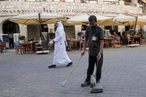 man sweeping street in front of outdoor eating area