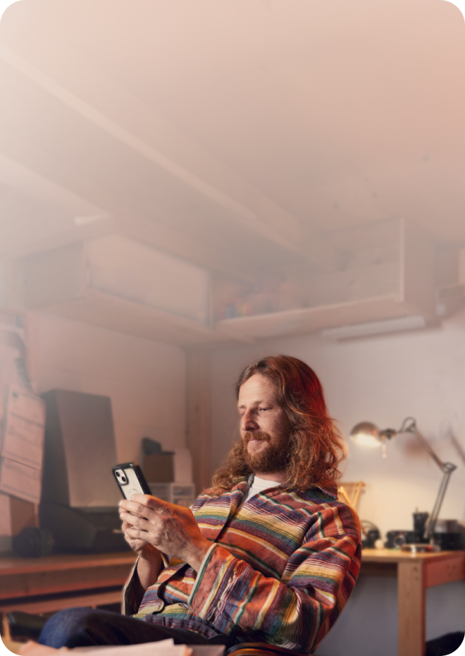 A TurboTax customer working on his phone and laptop in his workshop.