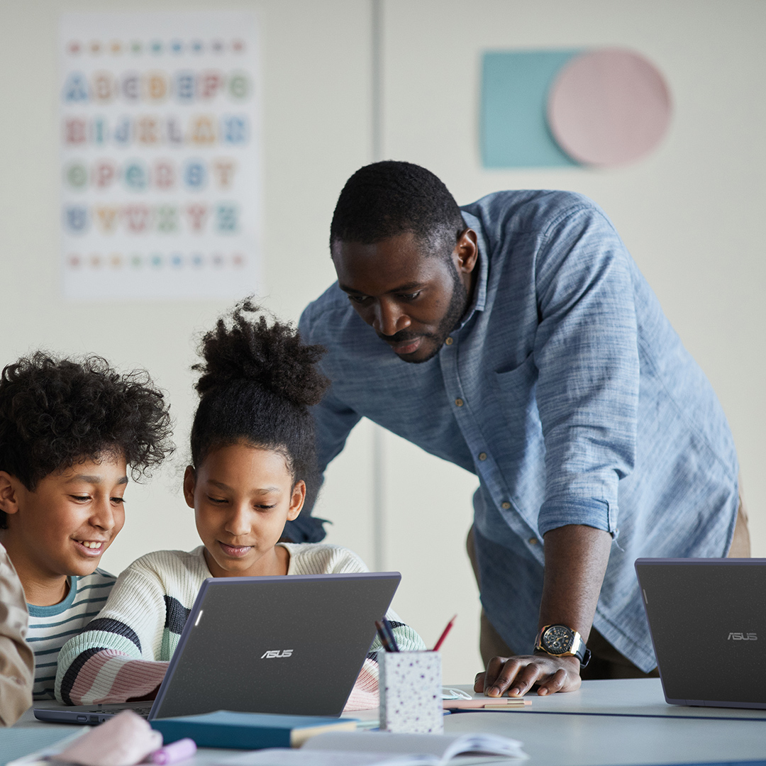 A teacher is looking at  ASUS ExpertBook B3 Flip to give remote lesson in her room, while one hand is writing on a whiteboard behind her.