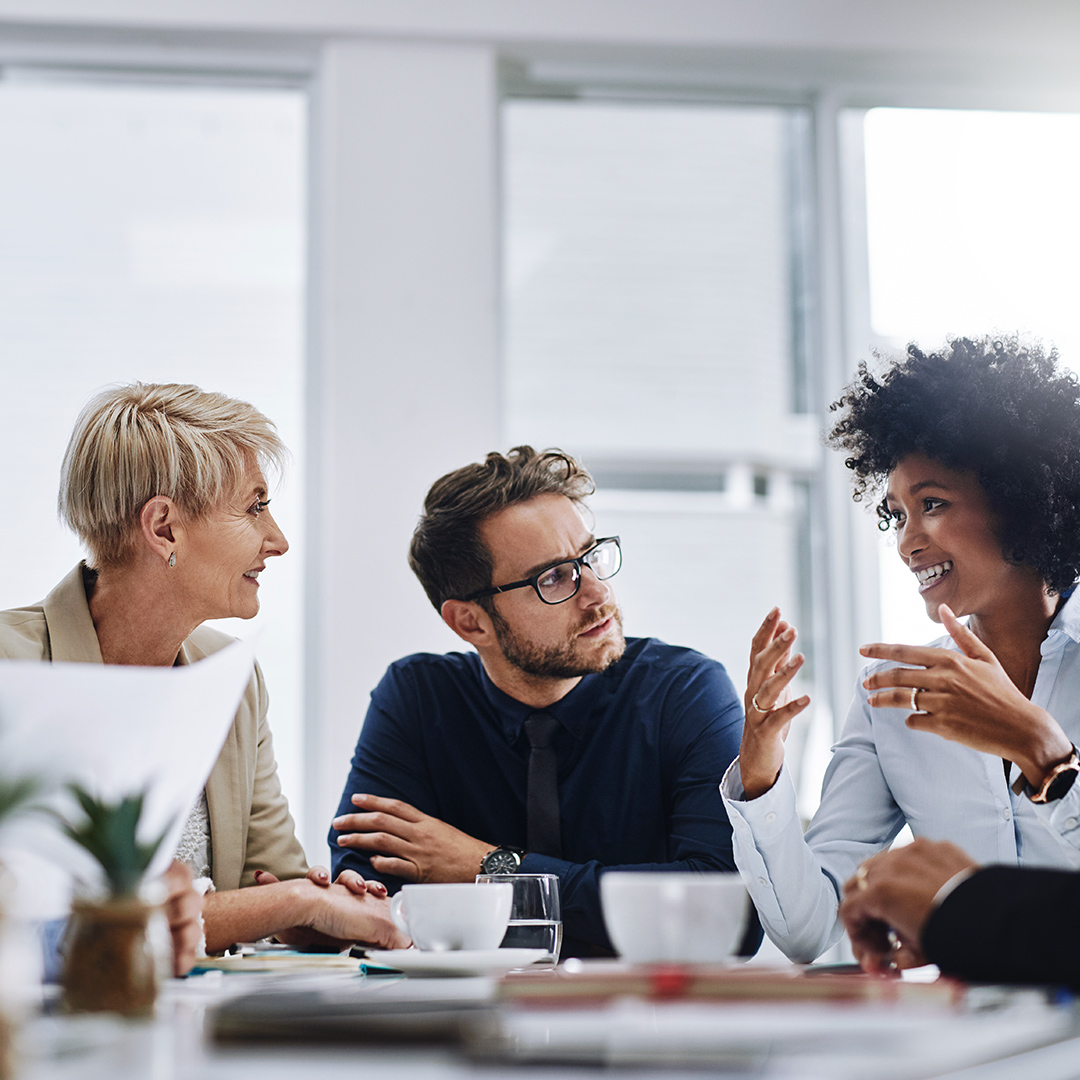 Four employees are discussing together in a meeting room.