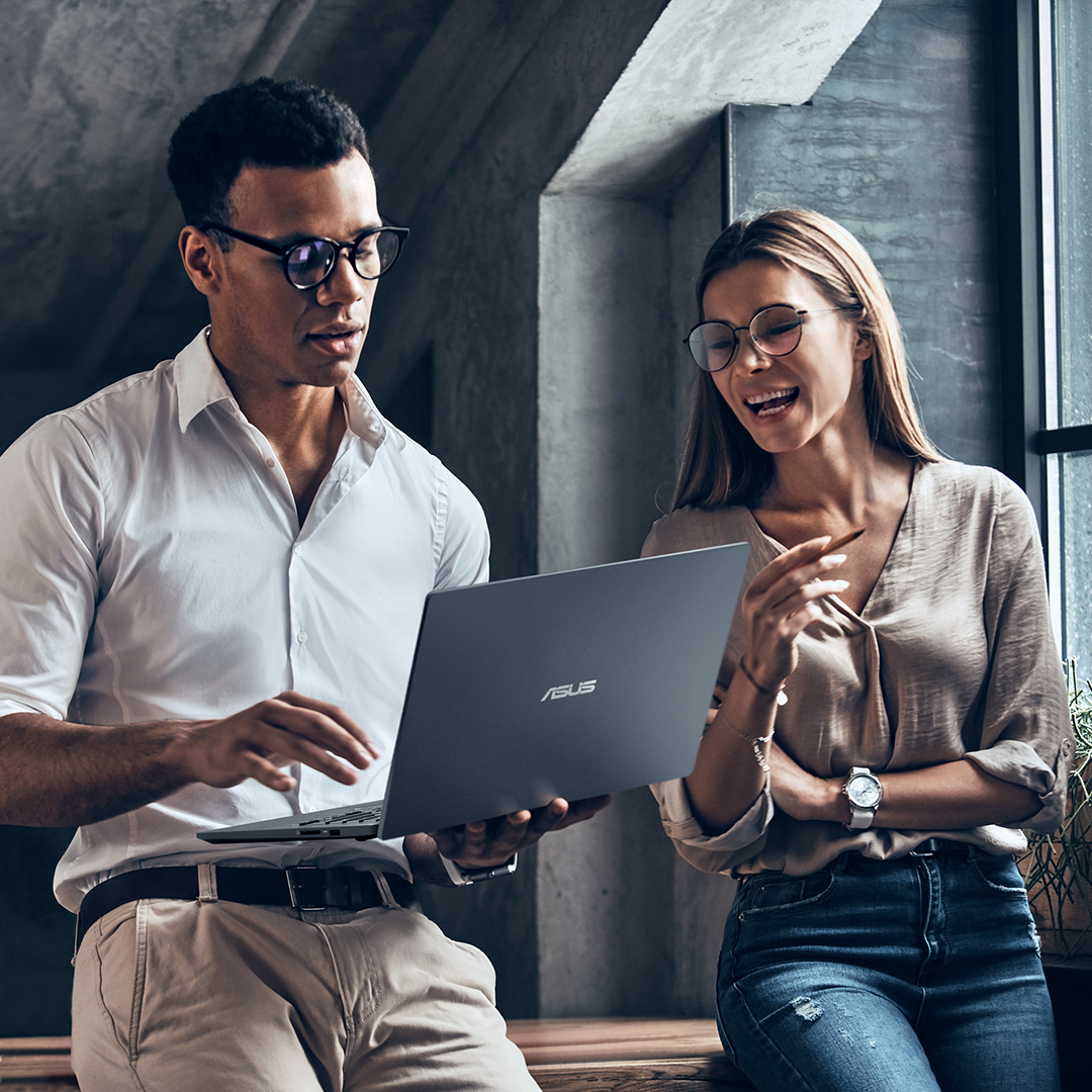 Two empolyees are discussing together happily with a ASUS laptop holding on hand.