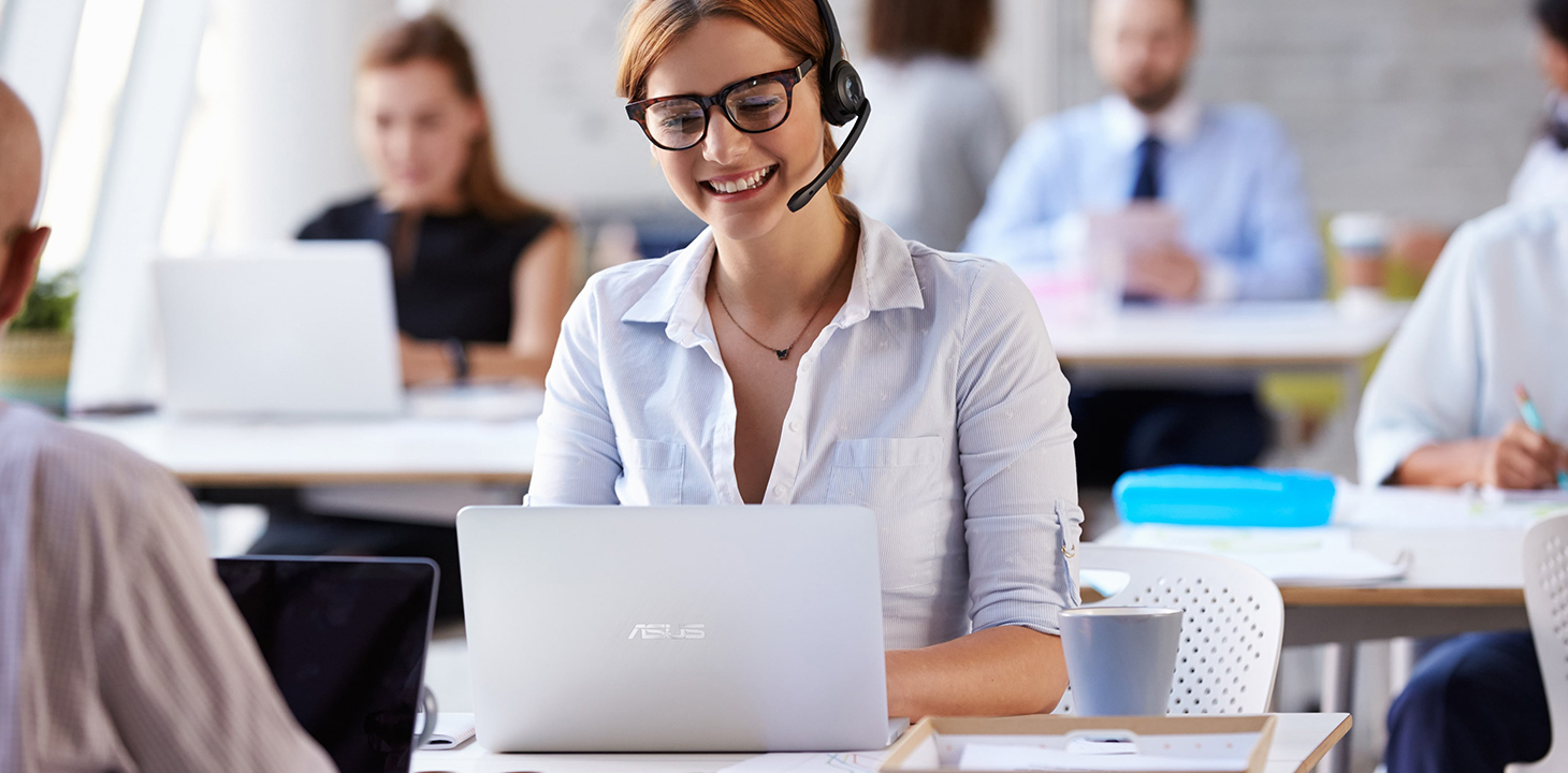 A customer service staff wearing headphone is talking on the call and using ASUS laptop.