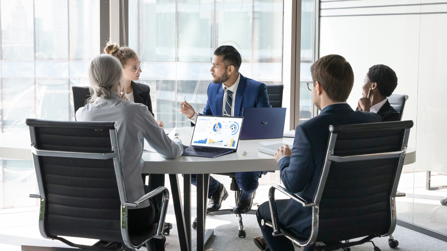 A group of employees are in a meeting room with ASUS ExpertBook laptops on the desk.