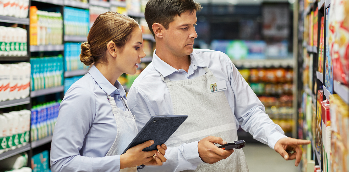 Two supermarket staffs are checking the on-shelf products together, holding ASUS ExpertBook B3 detachable laptop on hand.