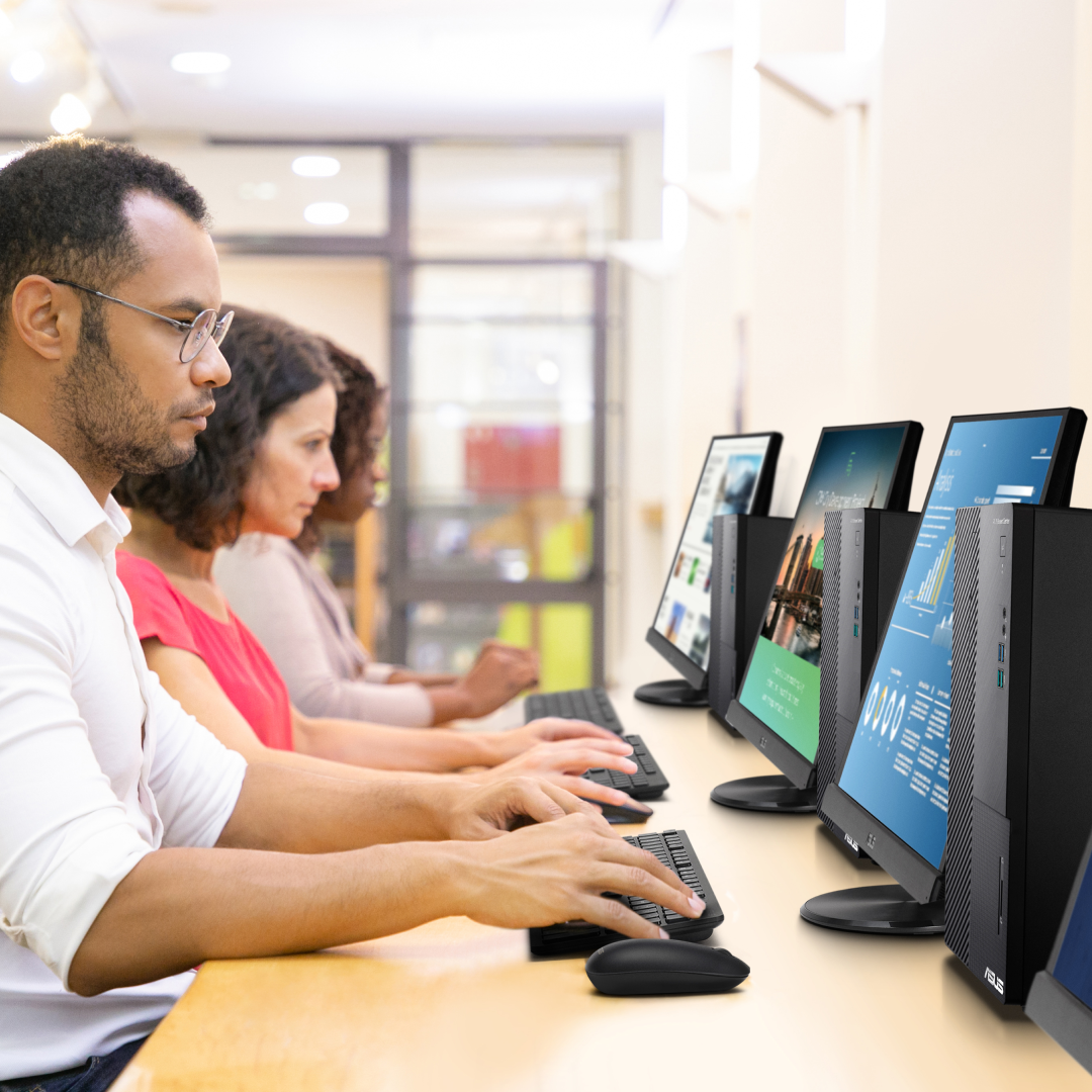 Three people are using desktops at a public area.