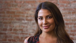 Portrait Of Smiling Hispanic Woman Standing Against Brick Wall In Coffee Shop