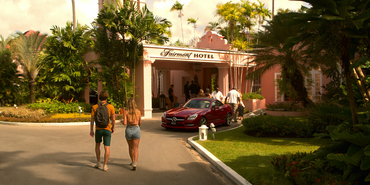 John B and Sarah walk toward the pink Fairmont Hotel.