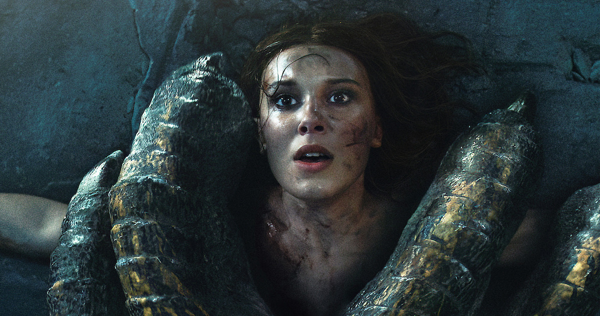 Millie Bobby Brown as Princess Elodie pinned to the ground by a dragon.