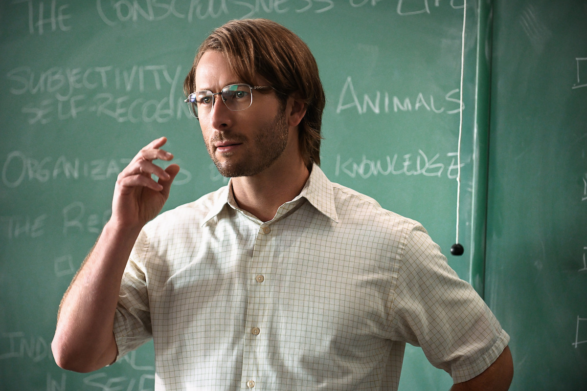 Glen Powell as Gary standing in front of a chalkboard in ‘Hit Man’.