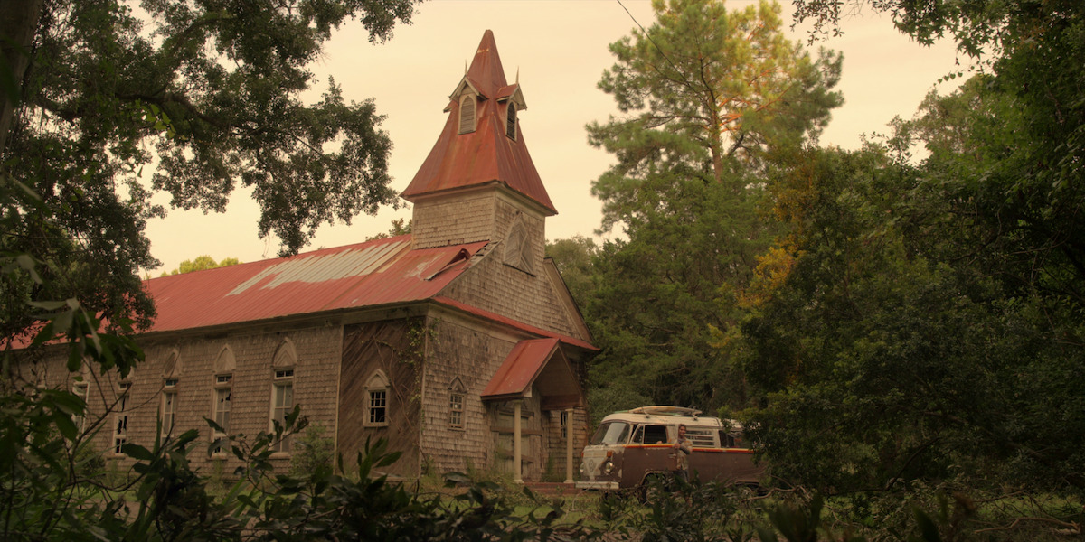 Exterior shot of a brick church with a red bell tower.