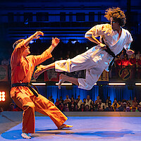 Xolo Maridueña as Miguel Diaz flies through the air kicking an opponent in Season 6 of 'Cobra Kai'