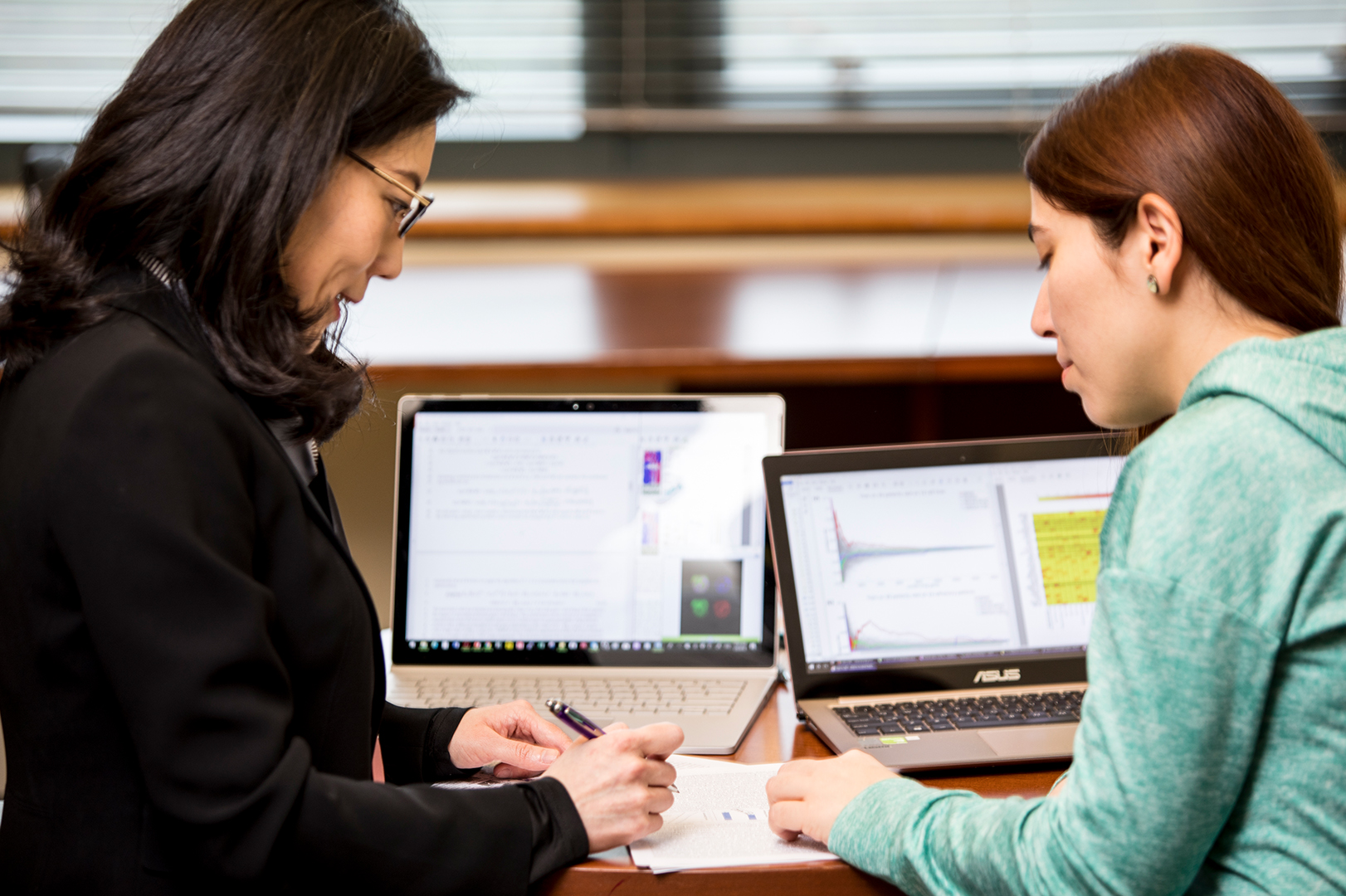 two people talk in front of laptops