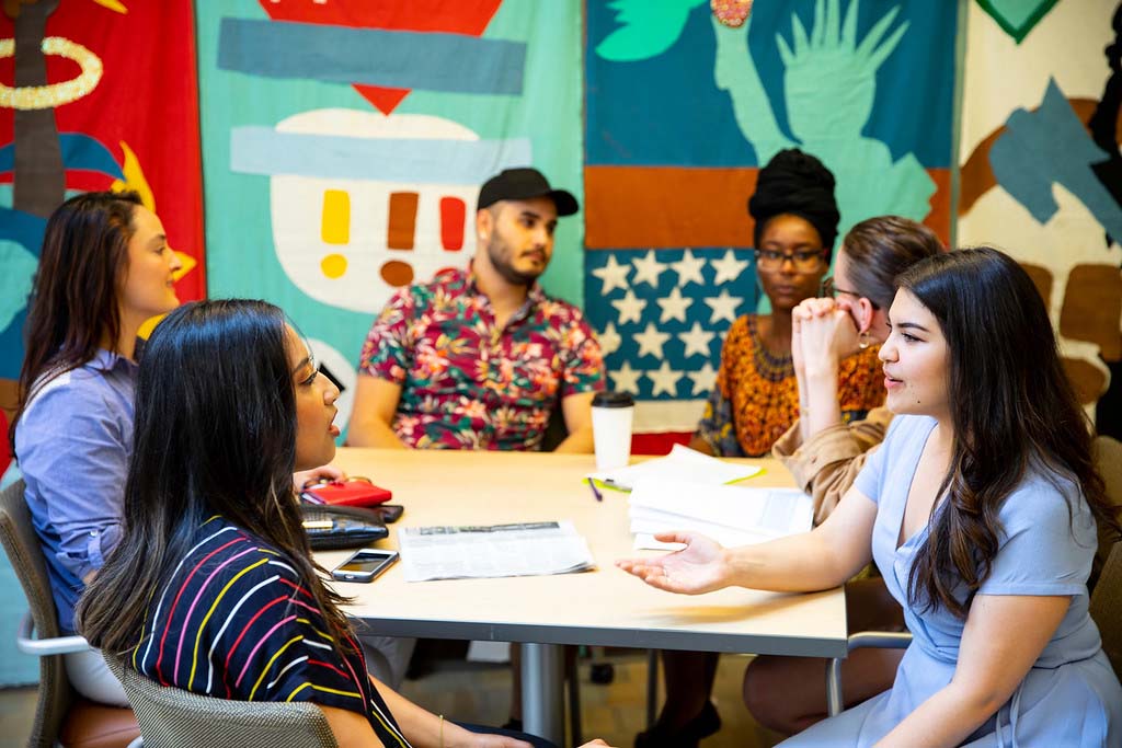 Colleagues sit around a table having a discussion.