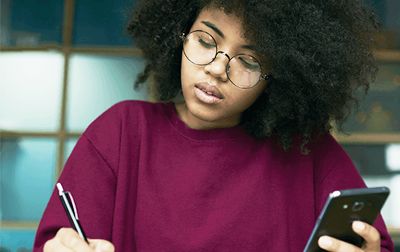 Mujer estudiando y sosteniendo un teléfono