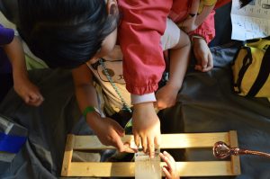 A kid touching an ice core that has a wire being pulled through it, testing if the ice has reformed behind it.