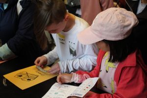 Two kids stamping a piece of paper with different types of faults.