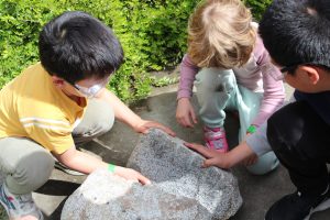 Two kids looking at a large rock after it was broken down the middle.