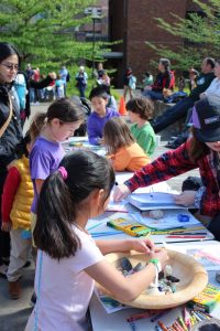 Kids surround a table outside coloring in geology-themed coloring pages.