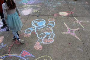 A chalk drawing of an astronaut, surrounded by other chalk drawings.