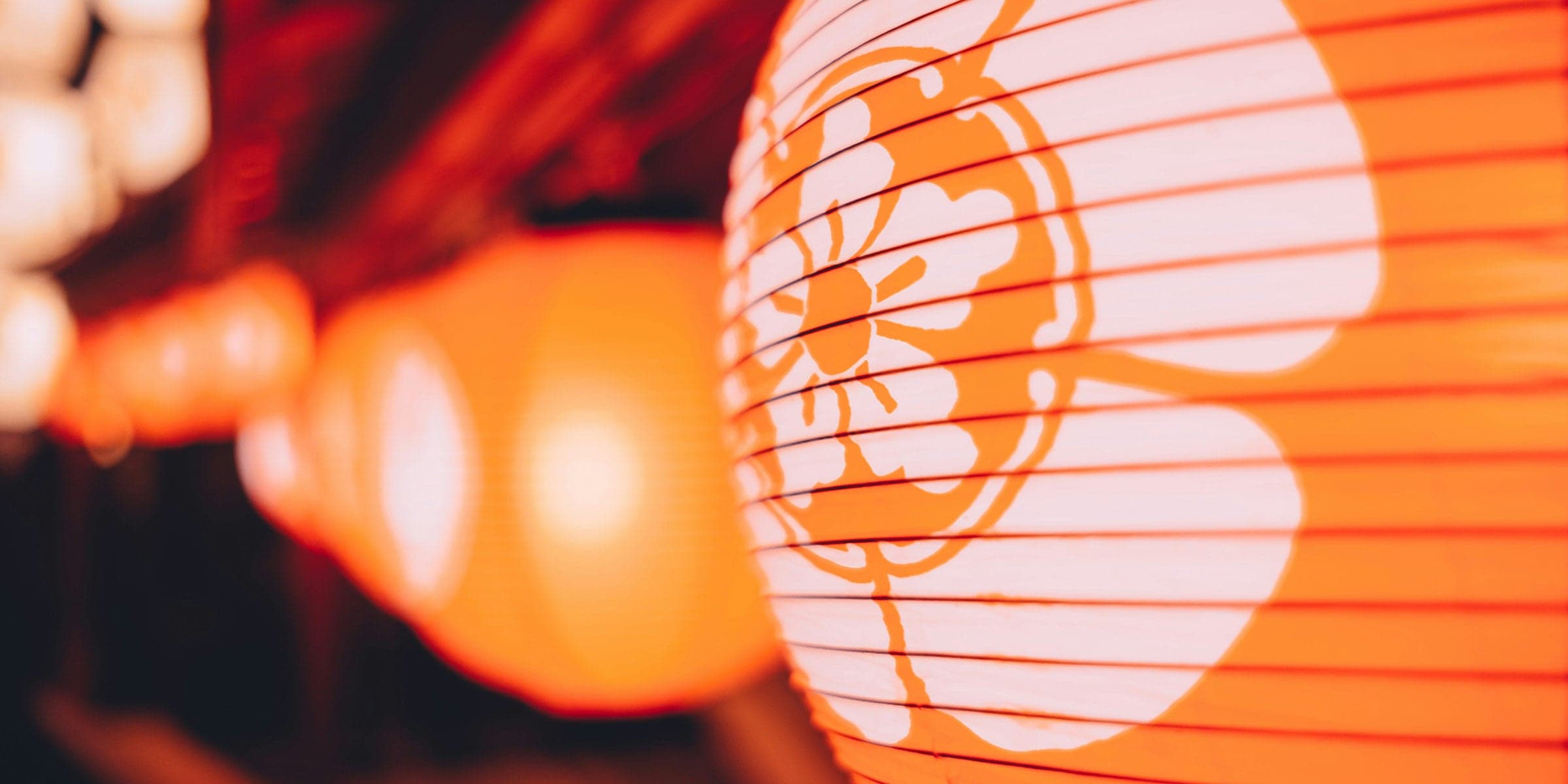 A bright orange lantern with a white flower printed on it.