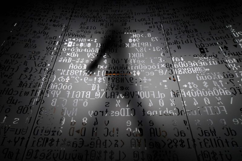 An employee walks behind a glass wall with machine coding symbols at the headquarters of the internet security giant Kaspersky in Moscow on Oct. 17, 2016.