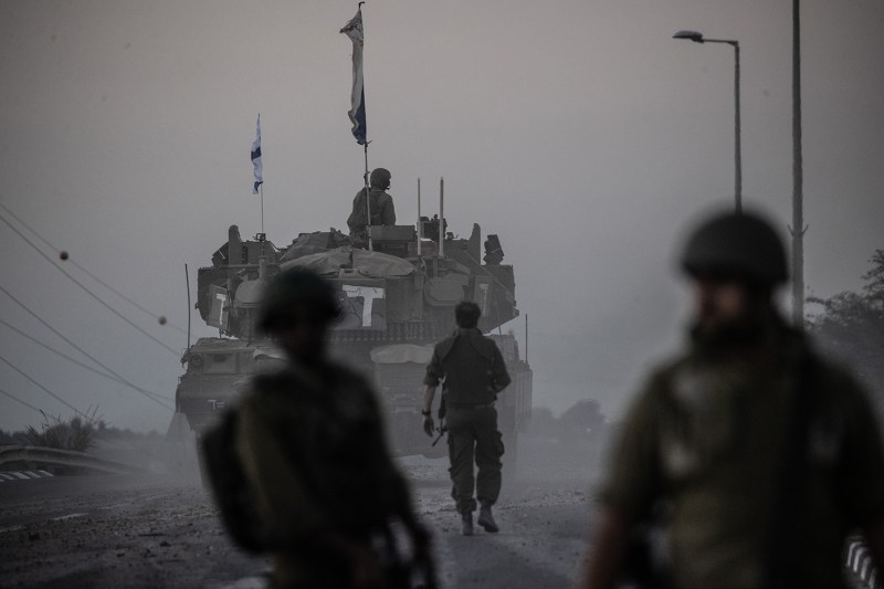 Israeli soldiers and and a tank are silhouetted on a hazy, dusty horizon as they move near the Gaza border as the Israeli army deploys military vehicles around the Gaza Strip.