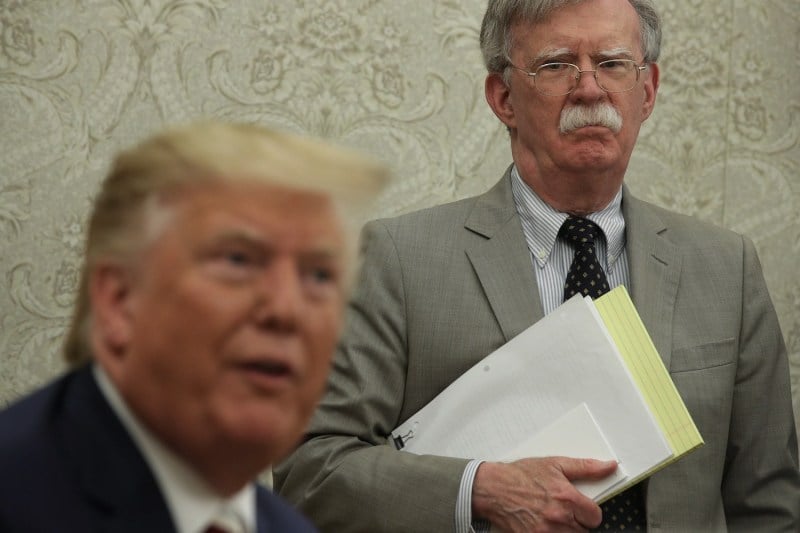 U.S. President Donald Trump on the left speaks to the media while National Security Advisor John Bolton listens nearby.